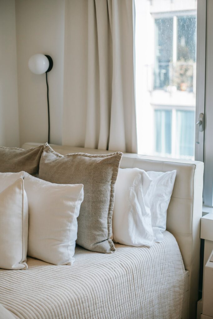 des coussins de couleurs différentes et de matériaux naturels différents sont posés sur un canapé en velours blanc