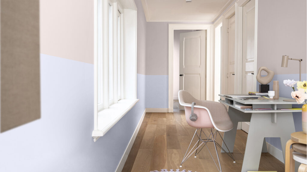 cette photo représente un bureau situé dans un couloir. Au sol, un parquet en bois massif. Le mur est peint de 2 couleurs : une peinture rose pastel en haut, un bleu pâle en bas