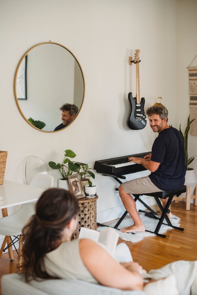 un homme est dans un salon et joue du piano, il semble heureux, il sourit