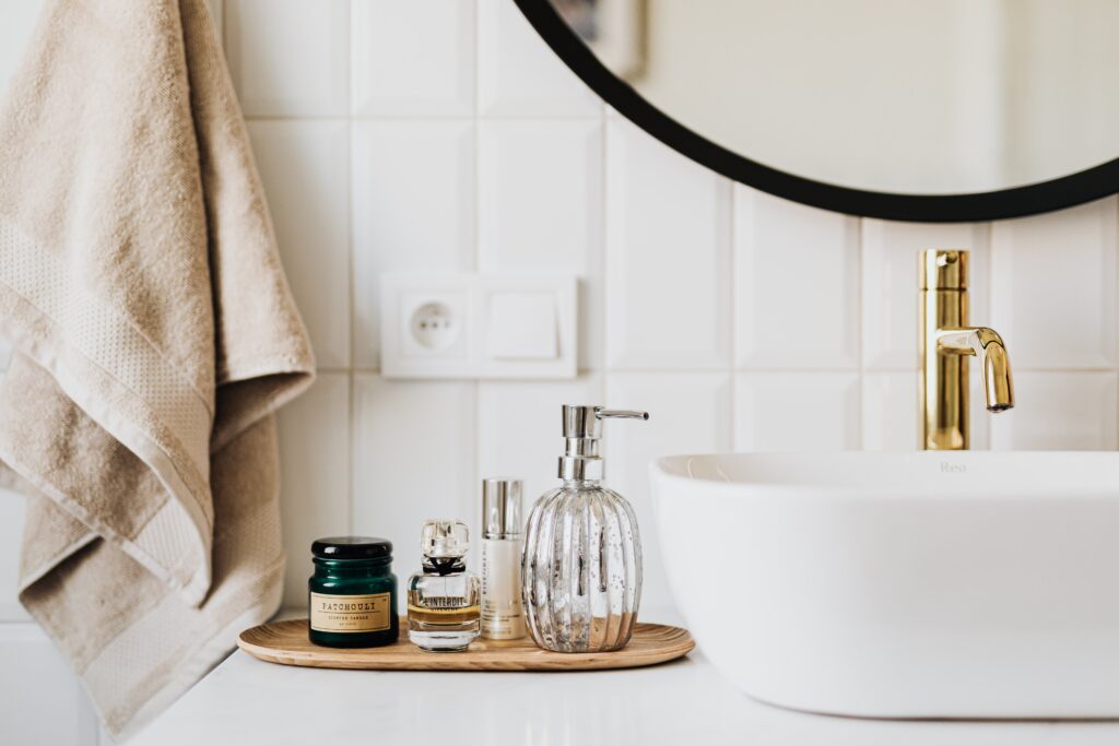 une salle de bain blanche, avec un carrelage mural blanc, des produits d'hygiene sont disposés sur le meuble vasque