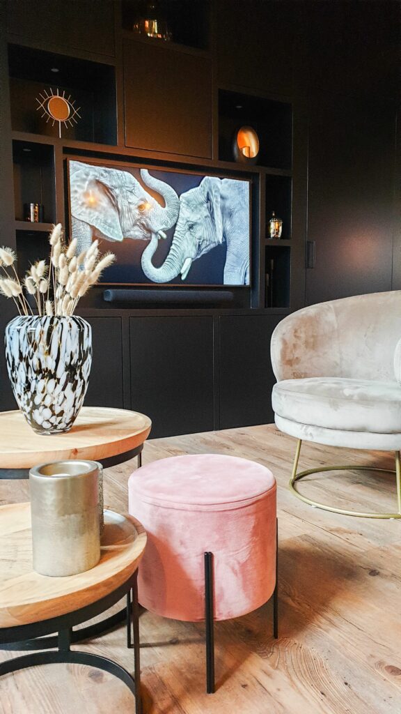 Télévision murale intégrée et camouflée sous la forme d'un tableau d'art dans un salon chaleureux et épuré.